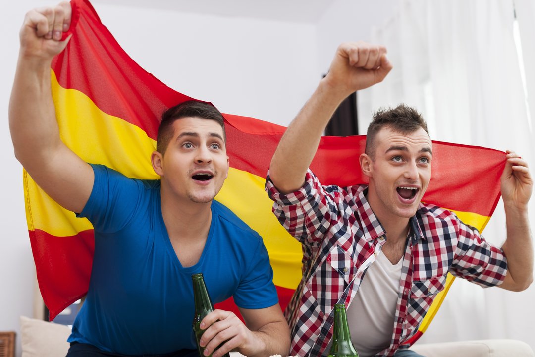 Men watching football match on TV and cheering of spanish team 